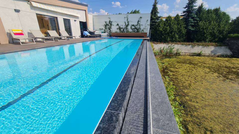 Designerski basen z rynna przelewową. Wykończenie z kamienia naturalnego. Designerski basen z rynna przelewową. Wykończenie z kamienia naturalnego.